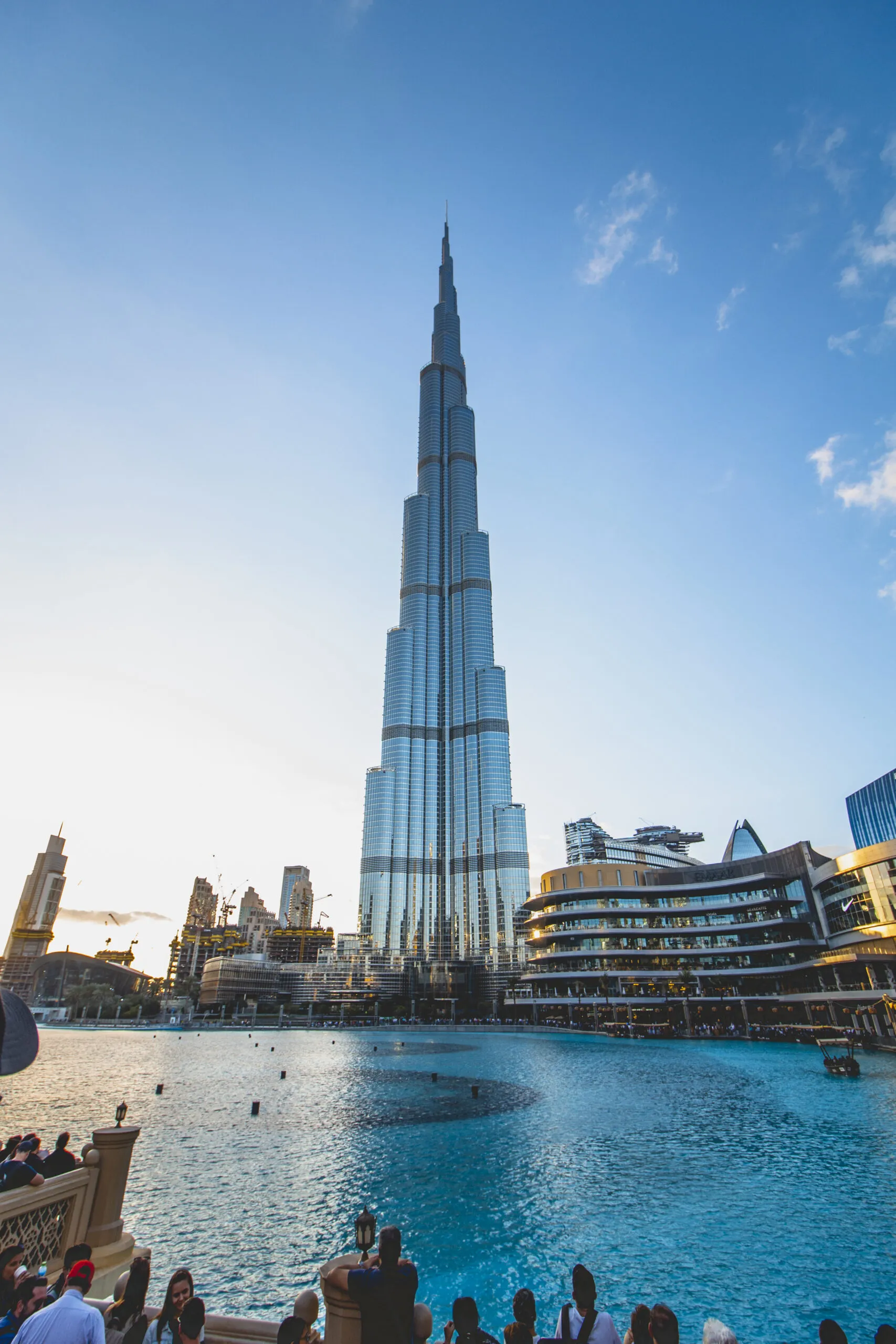 Glass facade of The Residence Burj Khalifa in Downtown Dubai with Emaar skyscrapers and lush palm trees